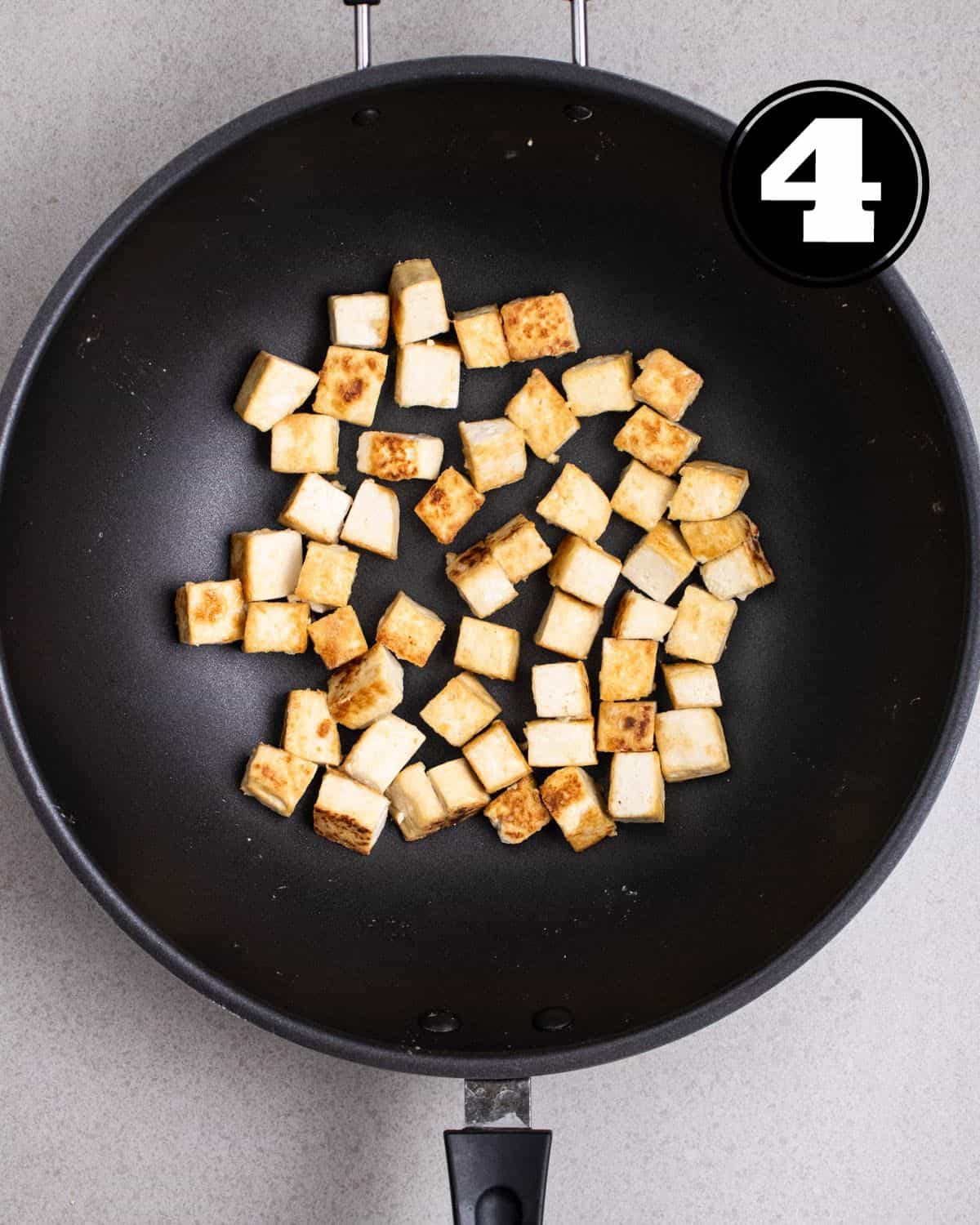 Pan-fried tofu in a wok.
