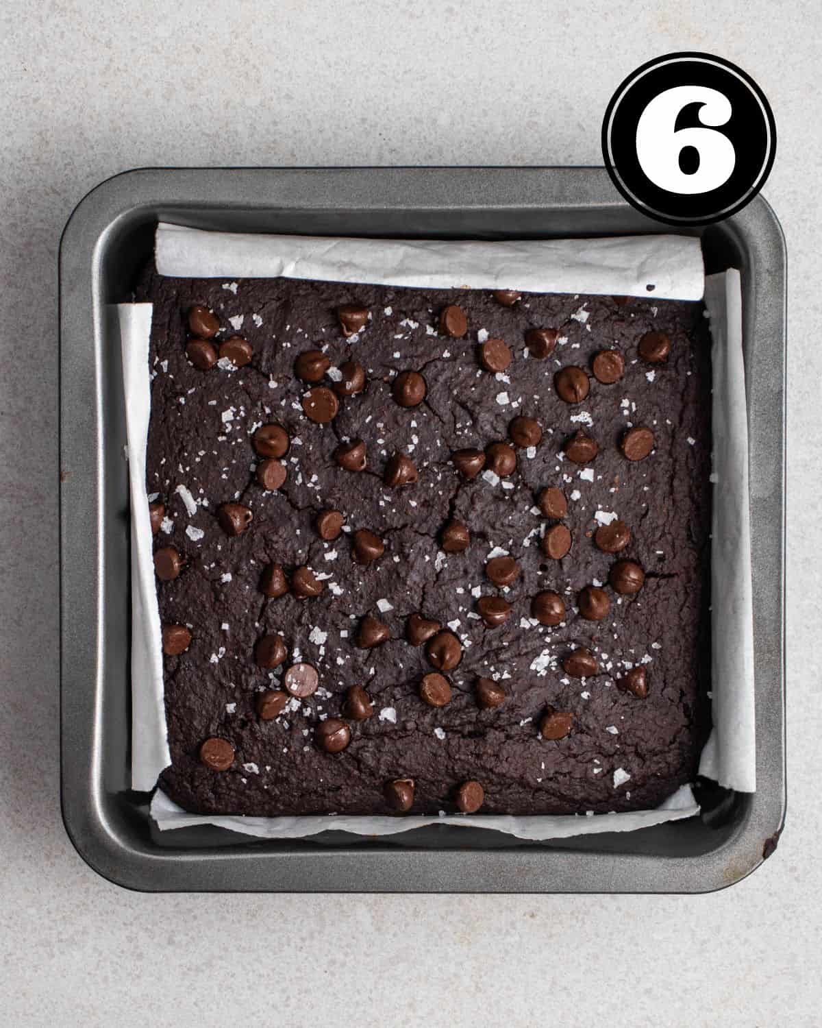Baked brownies in a square pan lined with parchment paper.