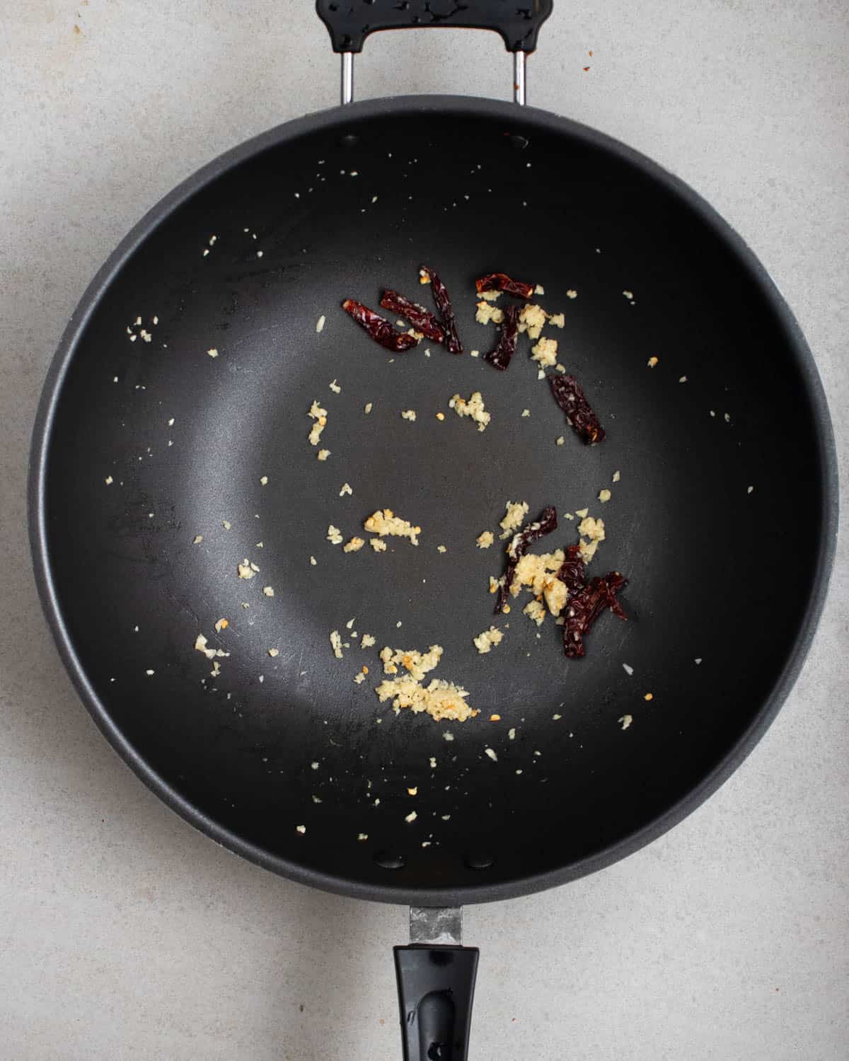 Cooked garlic and dried chilies in a wok.