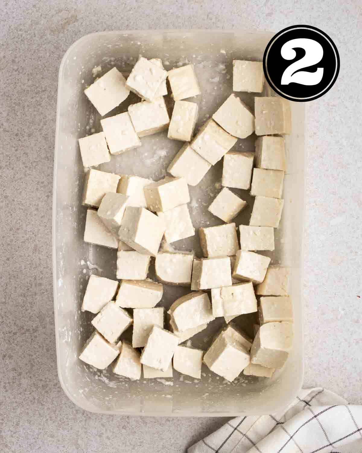Tofu cubes coated in cornstarch in a container.