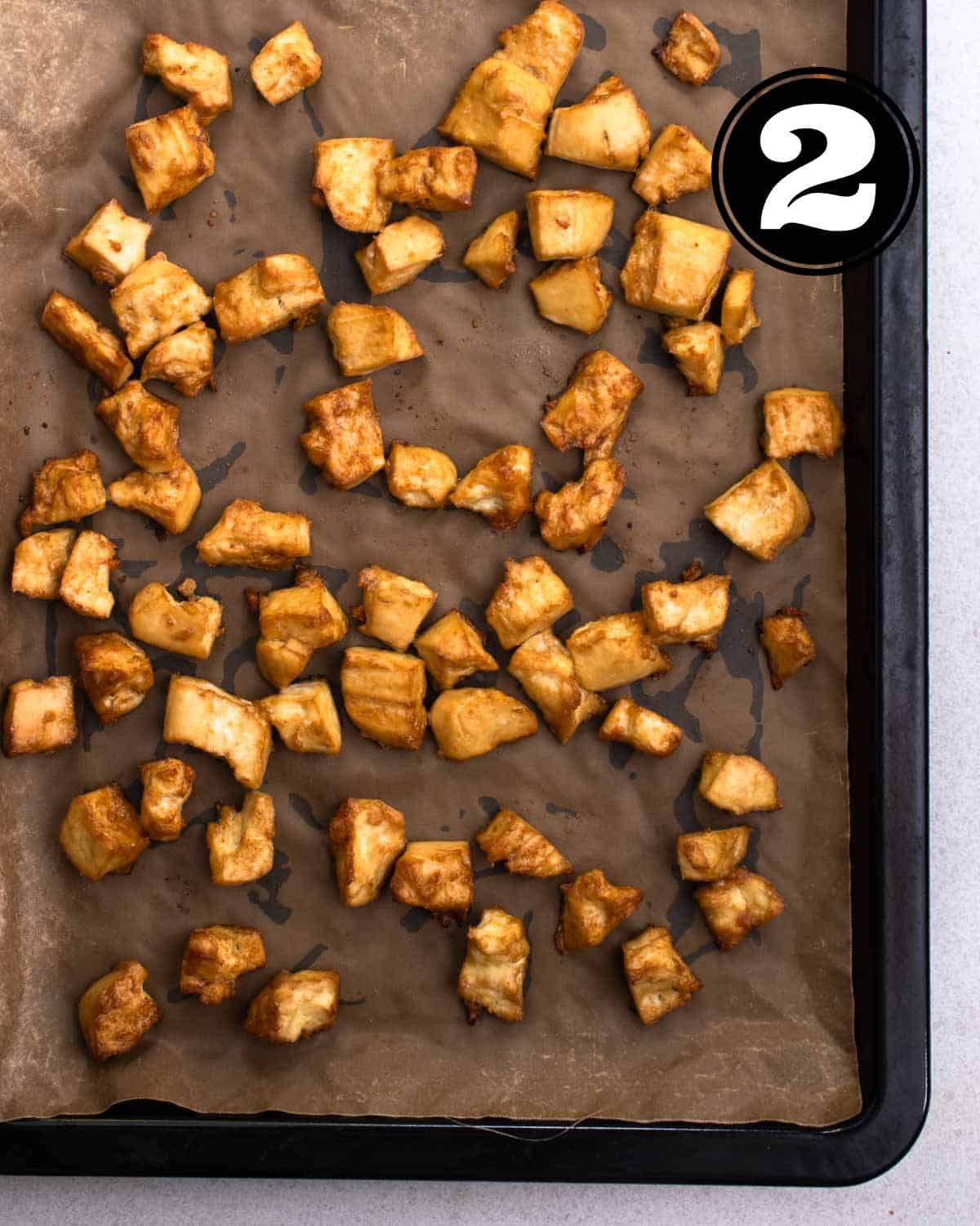 Baked tofu pieces on a baking sheet lined with parchment paper.
