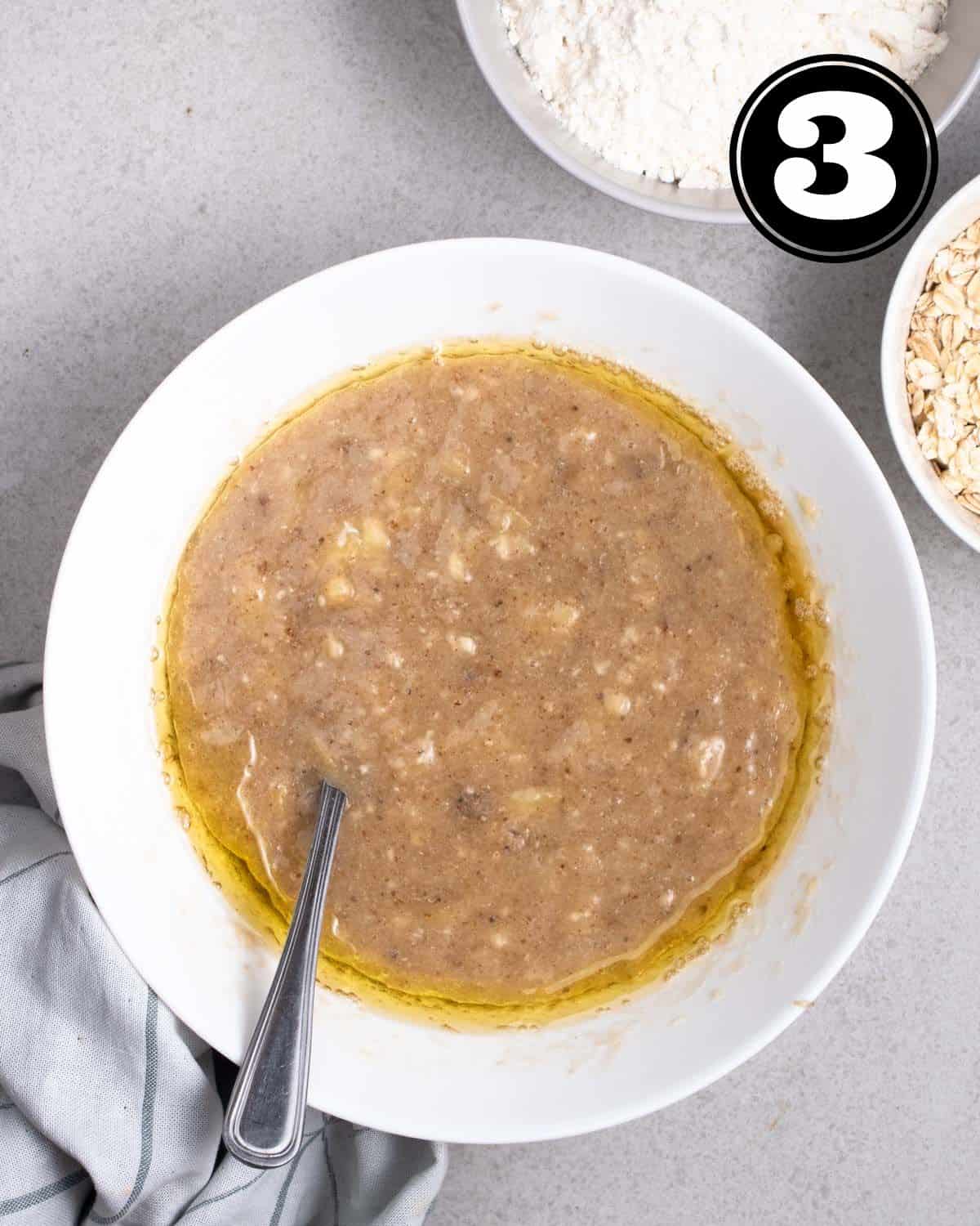 Wet ingredients in a bowl wirh bowl of flour and oats beside.