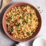 A pan of curry fried rice with a wooden spatula beside.