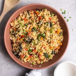 A pan of curry fried rice with a wooden spatula beside.