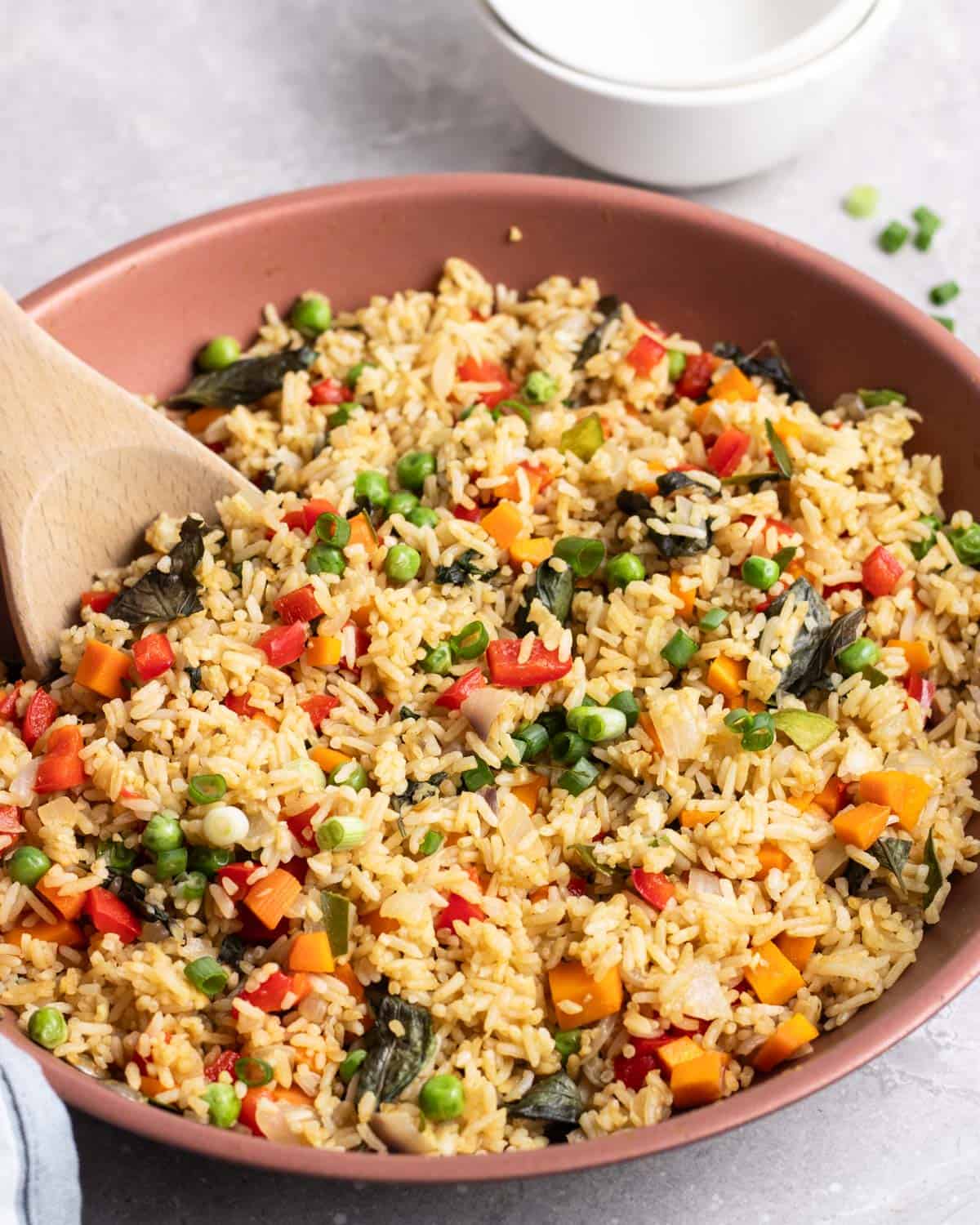 A pan of curry fried rice with a wooden spatula beside.