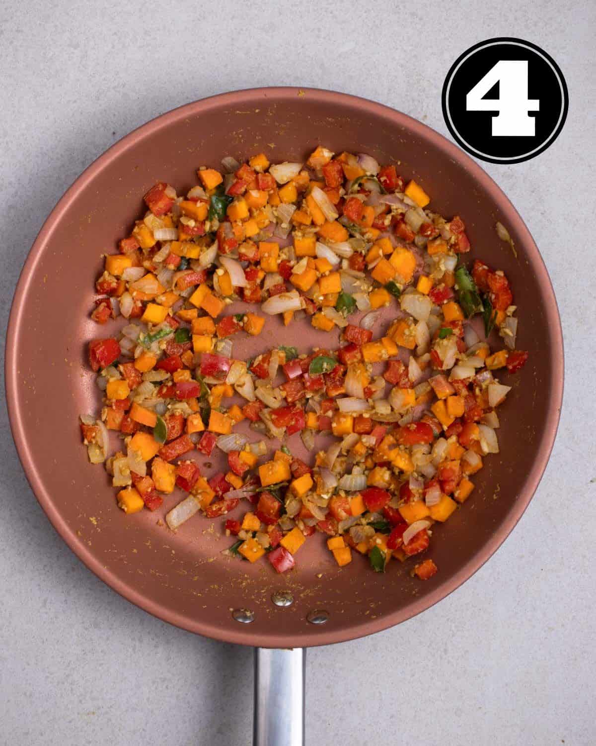 Cooked carrot, red pepper, and onion in a non-stick pan.