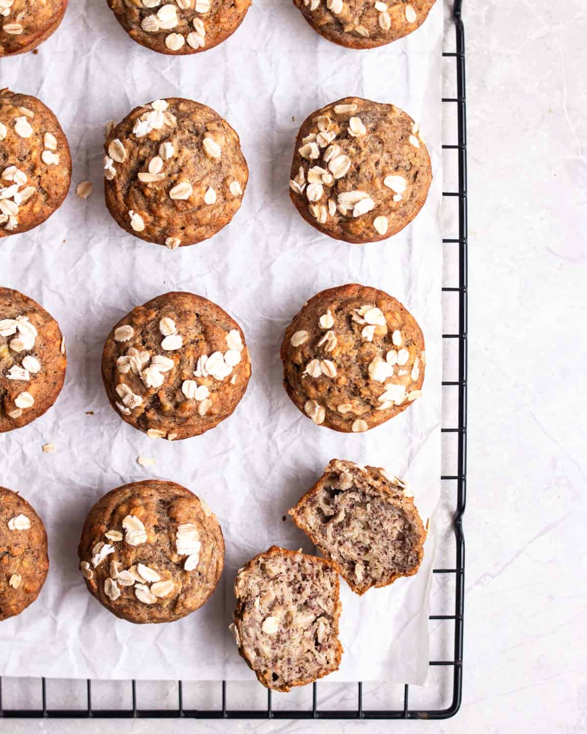 Muffins arranged on a baking tray lined with parchment paper with a muffin sliced in half.