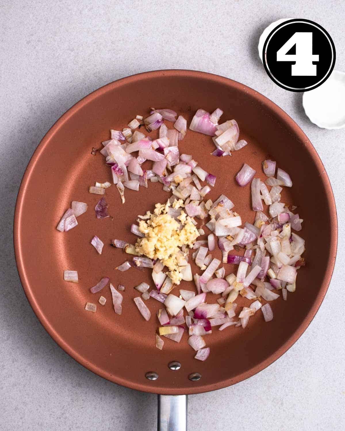 Adding garlic to a pan of cooked shallots.