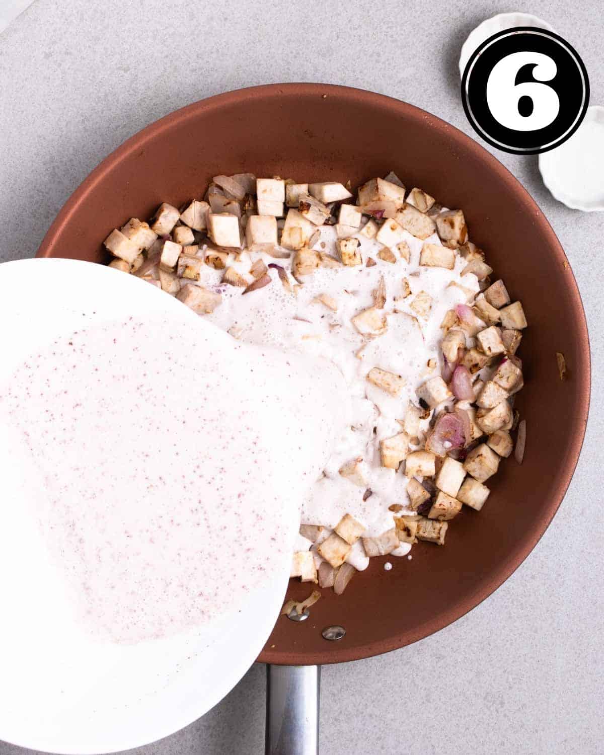 Pouring flour water mixture into a pan of cooked taro.