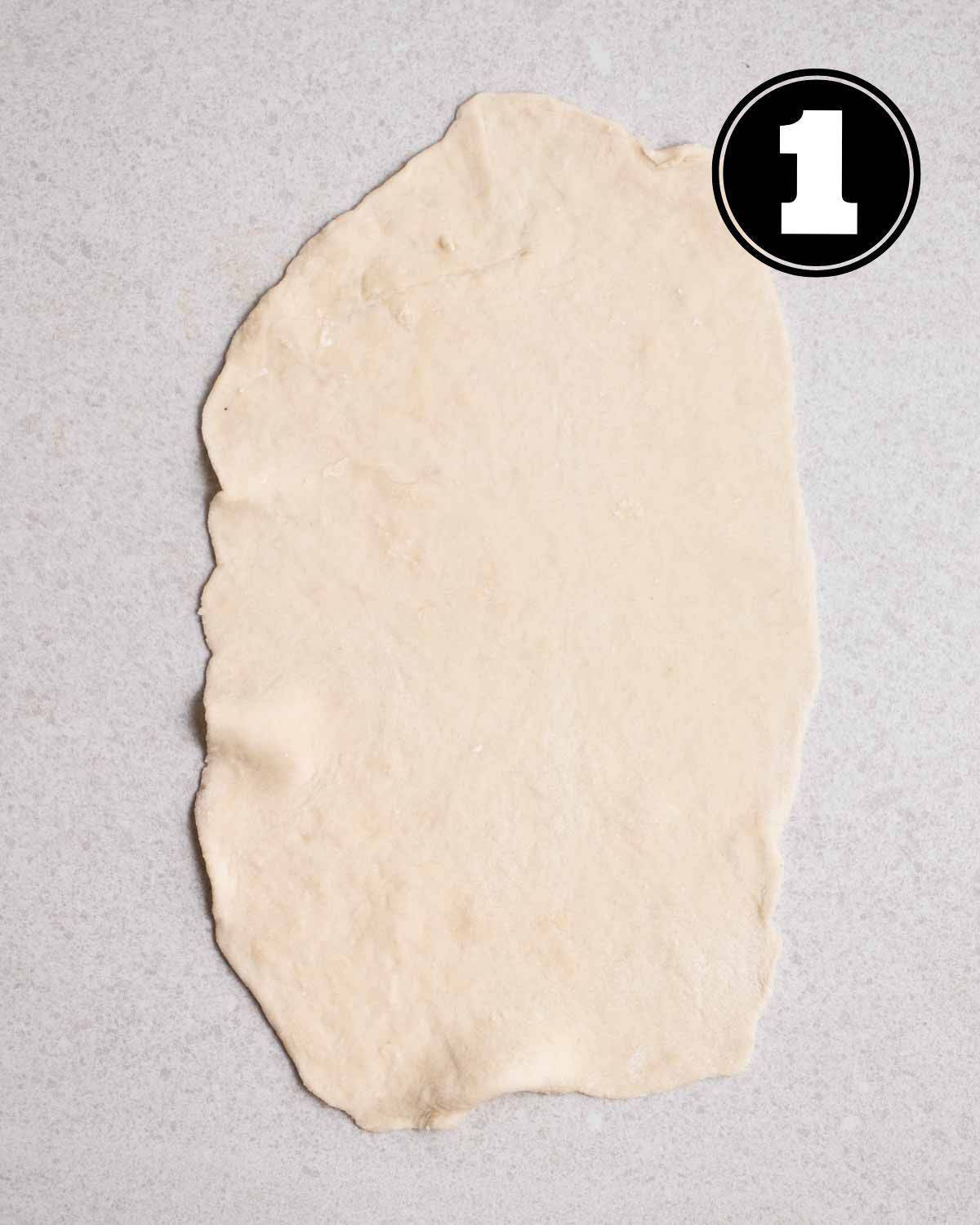 A rolled out dough on a grey surface.