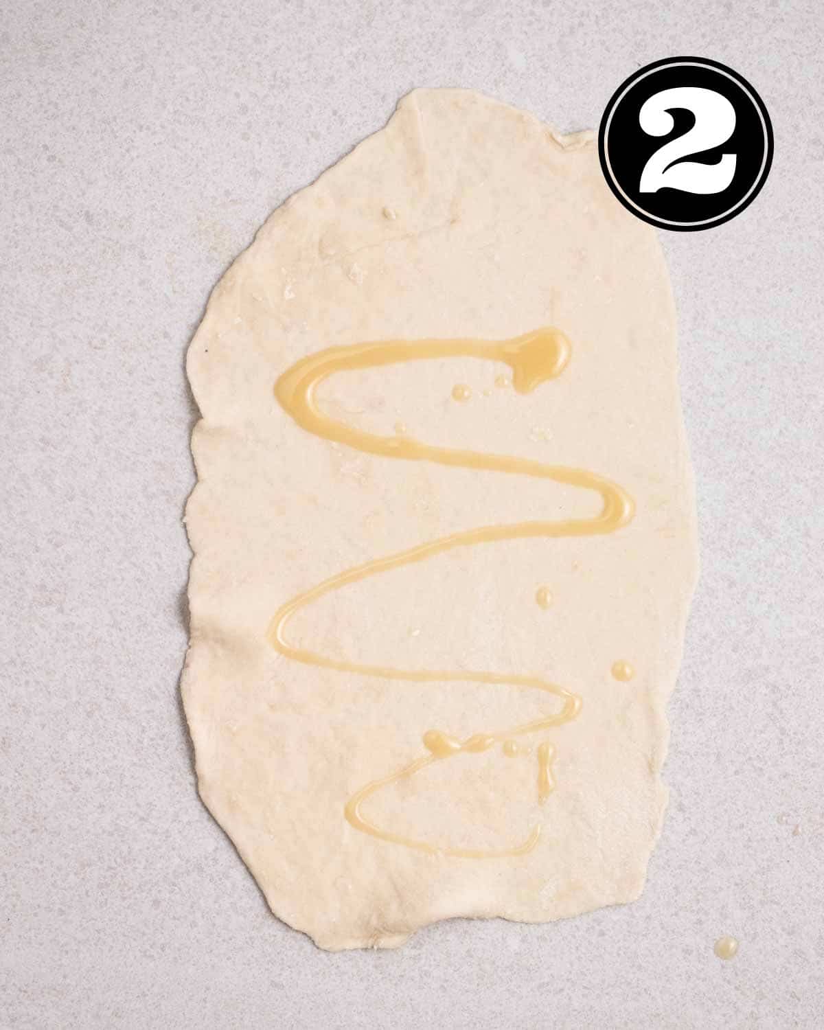 A rolled out dough with filling drizzled on it. 