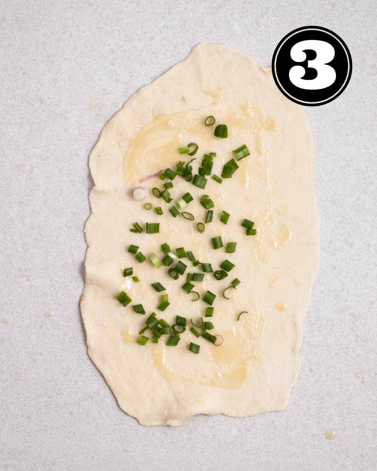 A rolled out dough with green onion sprinkled on. 