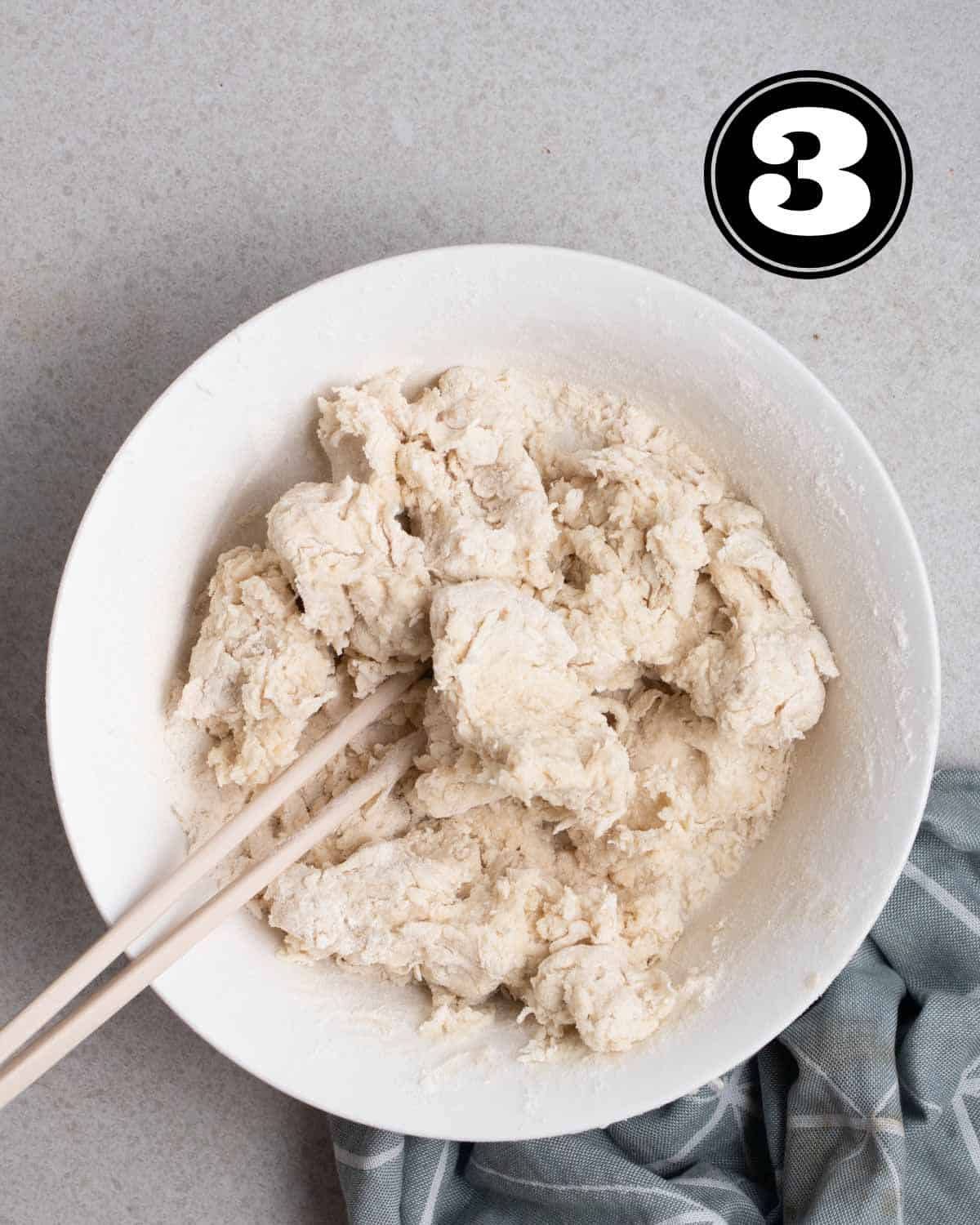 Dough in a bowl with a pair of chopsticks beside.