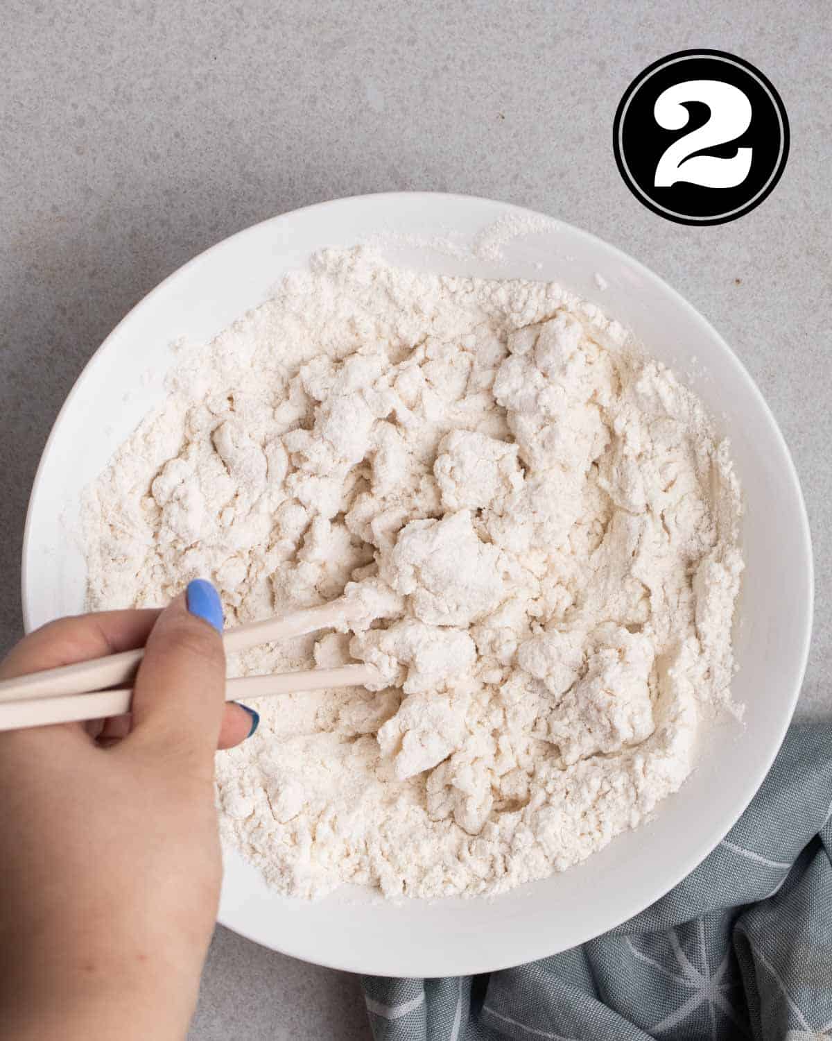 mixing dough with a pair of chopsticks on a white bowl.