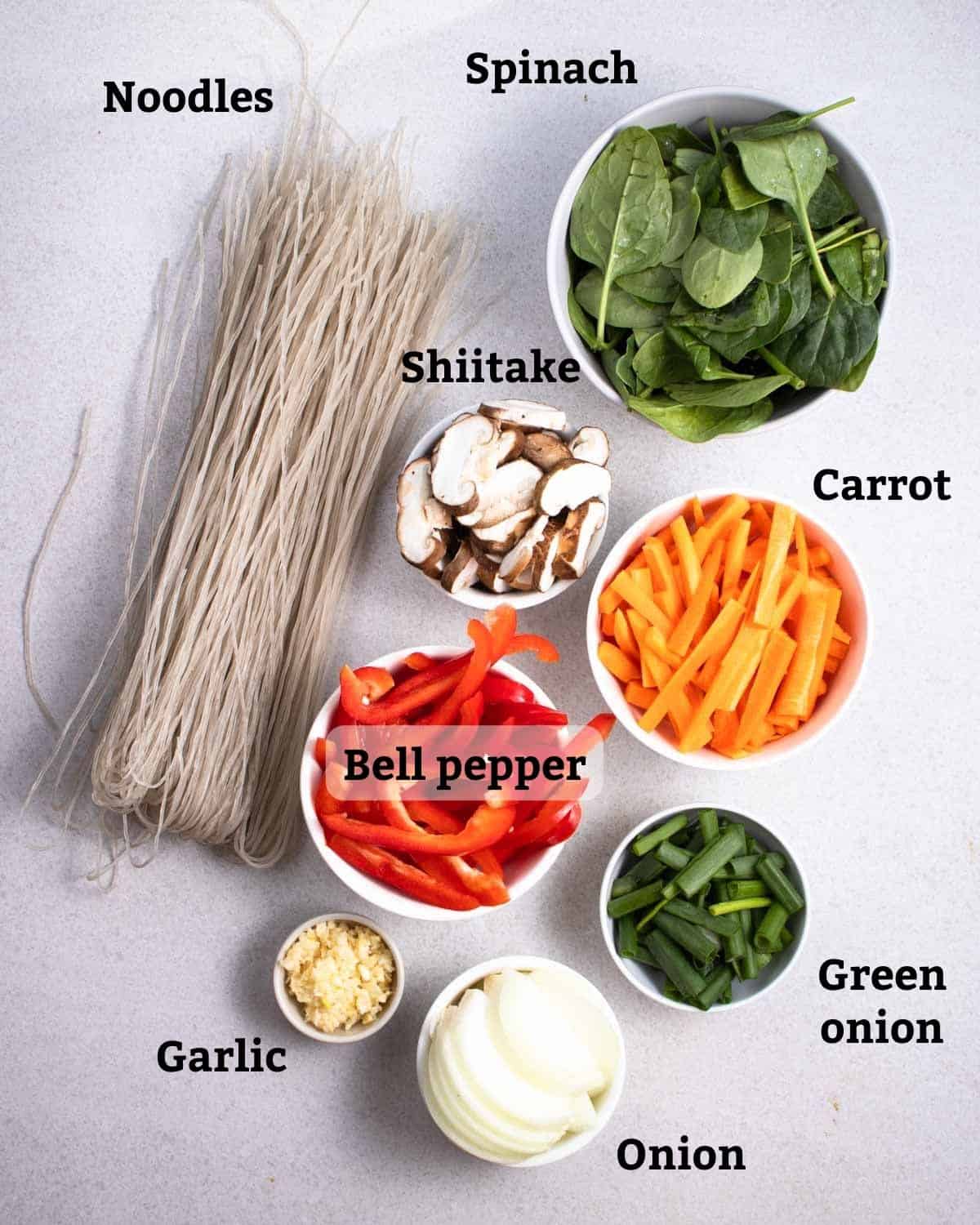 Ingredients needed like noodles, spinach, shiitake, carrot, bell pepper, green onion, garlic, and onion.