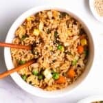 A bowl of fried rice served with chopsticks.