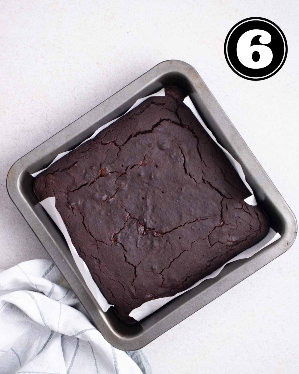 Baked brownies in a square baking tray lined with parchment paper.