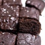 A tray of brownies arranged on a parchment paper topped with flaked sea salt.