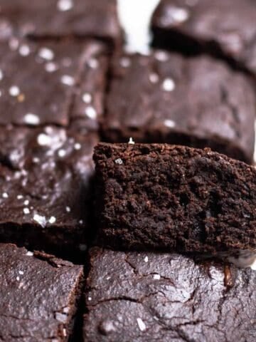 A tray of brownies arranged on a parchment paper topped with flaked sea salt.