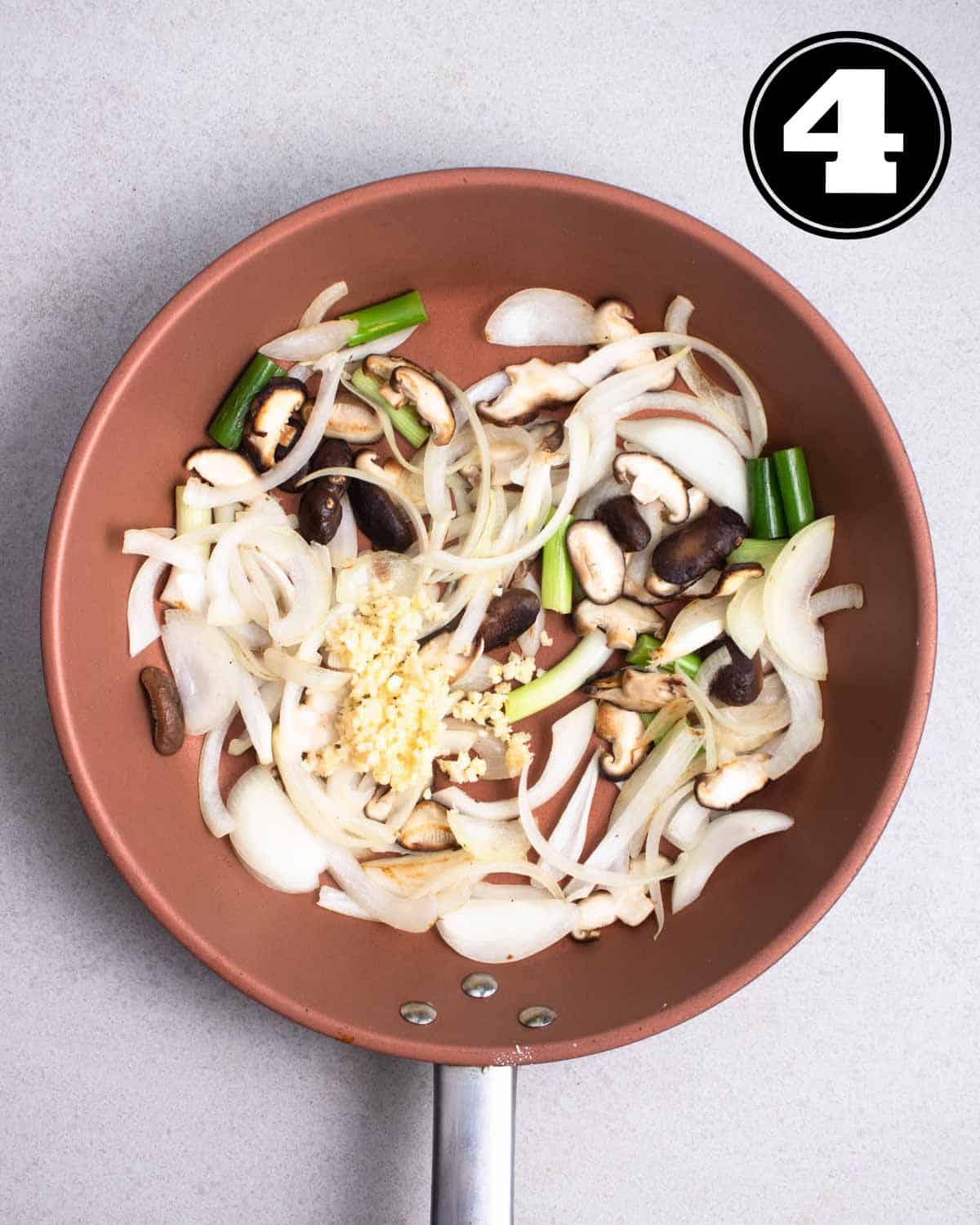 Cooked onion, mushrooms, and green onion in a non-stick pan.