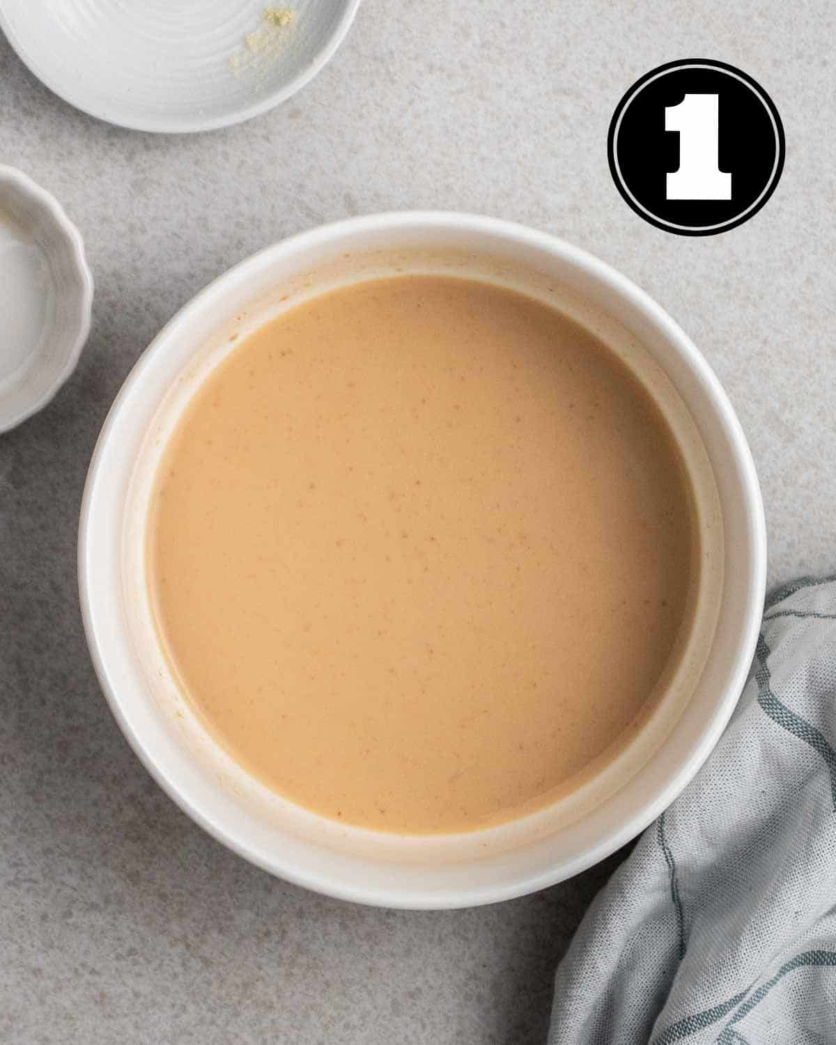 Buttermilk in a ramekin with 2 empty ramekins and a blue teacloth beside.