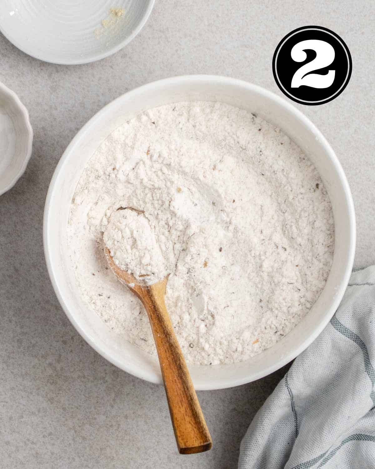 Dry ingredients in a bowl with a wooden spoon beside.