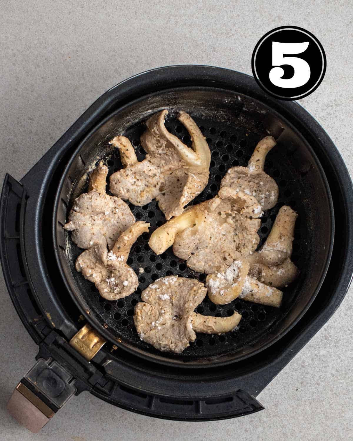 Uncooked oyster mushrooms in an air fryer container.