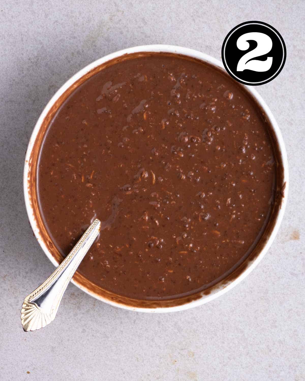 Overnight oats mixture in a bowl with a spoon beside.