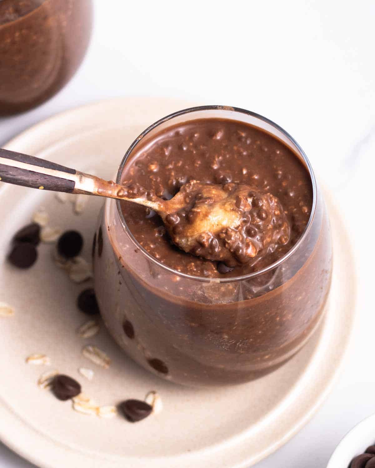 Spooning out some overnight oats from a jar with a teaspoon.