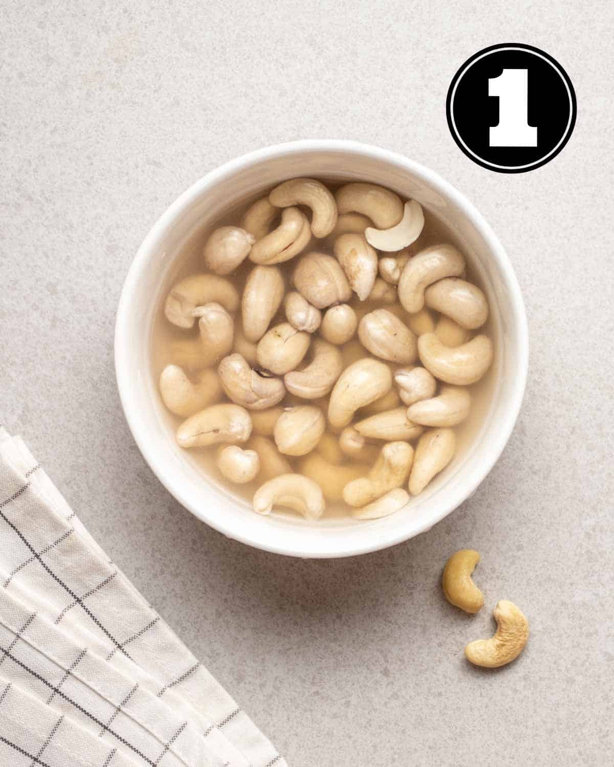 Soaking cashews in a ramekin with a teacloth beside.