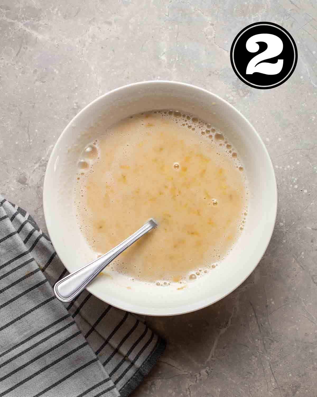 Wet ingredients in a bowl with a spoon beside.