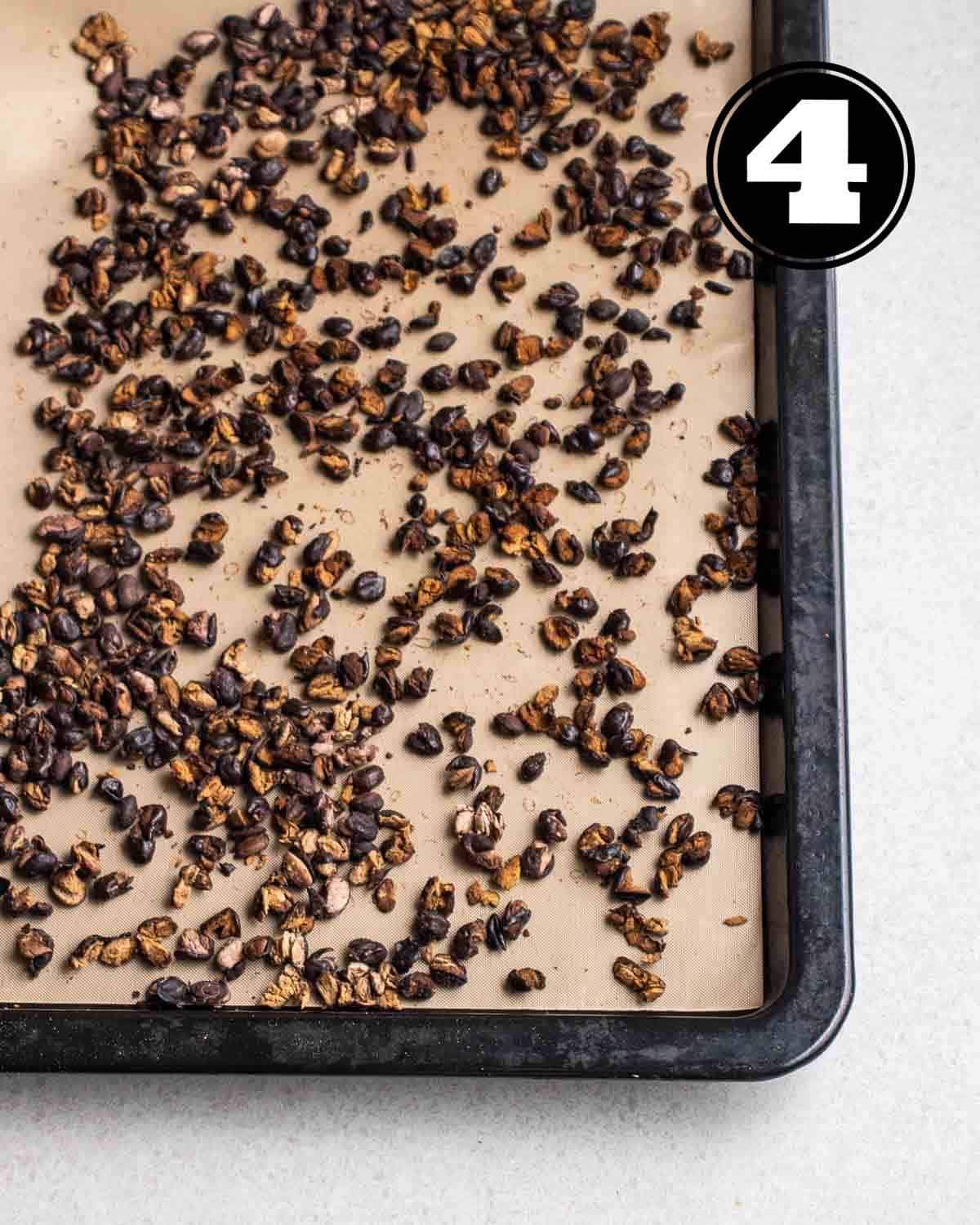 Roasted black beans on a black tray lined with parchment paper.