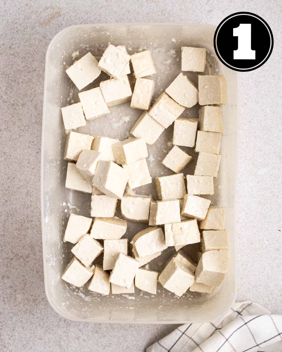 Tofu coated in cornstarch in a container.