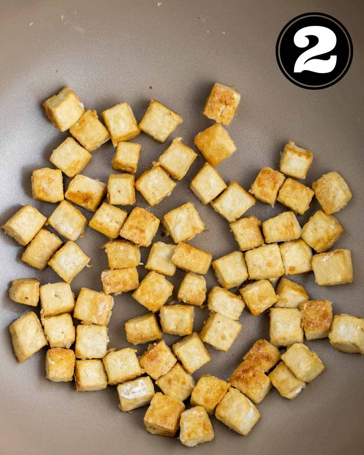 Pan-fried tofu in a wok.
