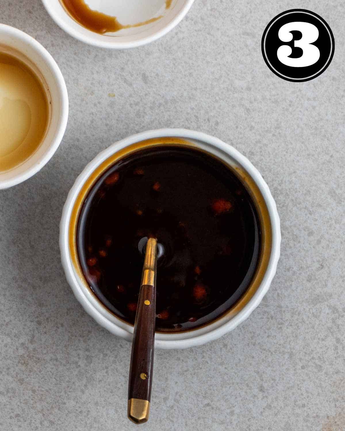 Stir-fry sauce in a ramekin with a teaspoon beside with 2 sauce dishes beside.