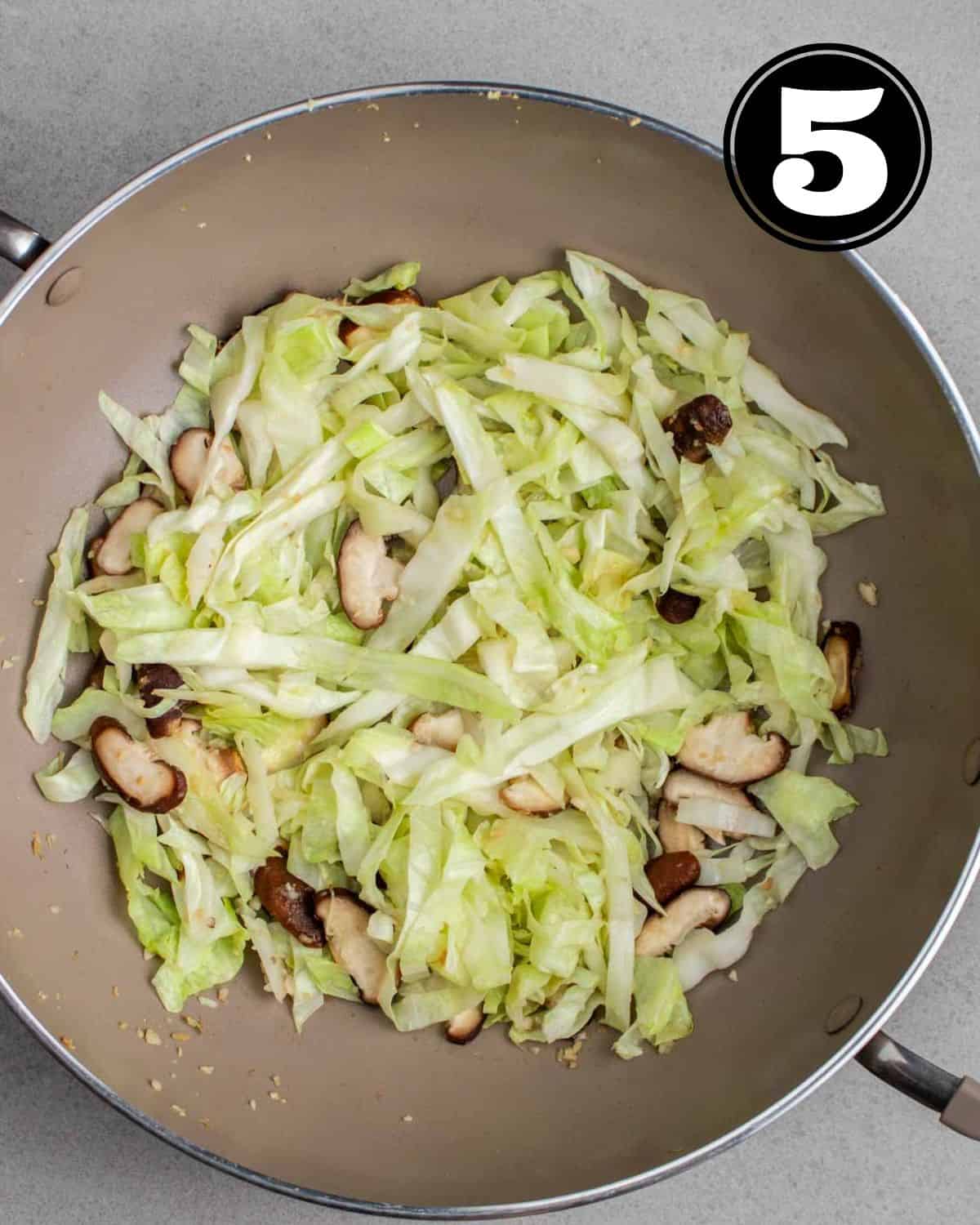 Cooked cabbage and mushrooms in a wok.