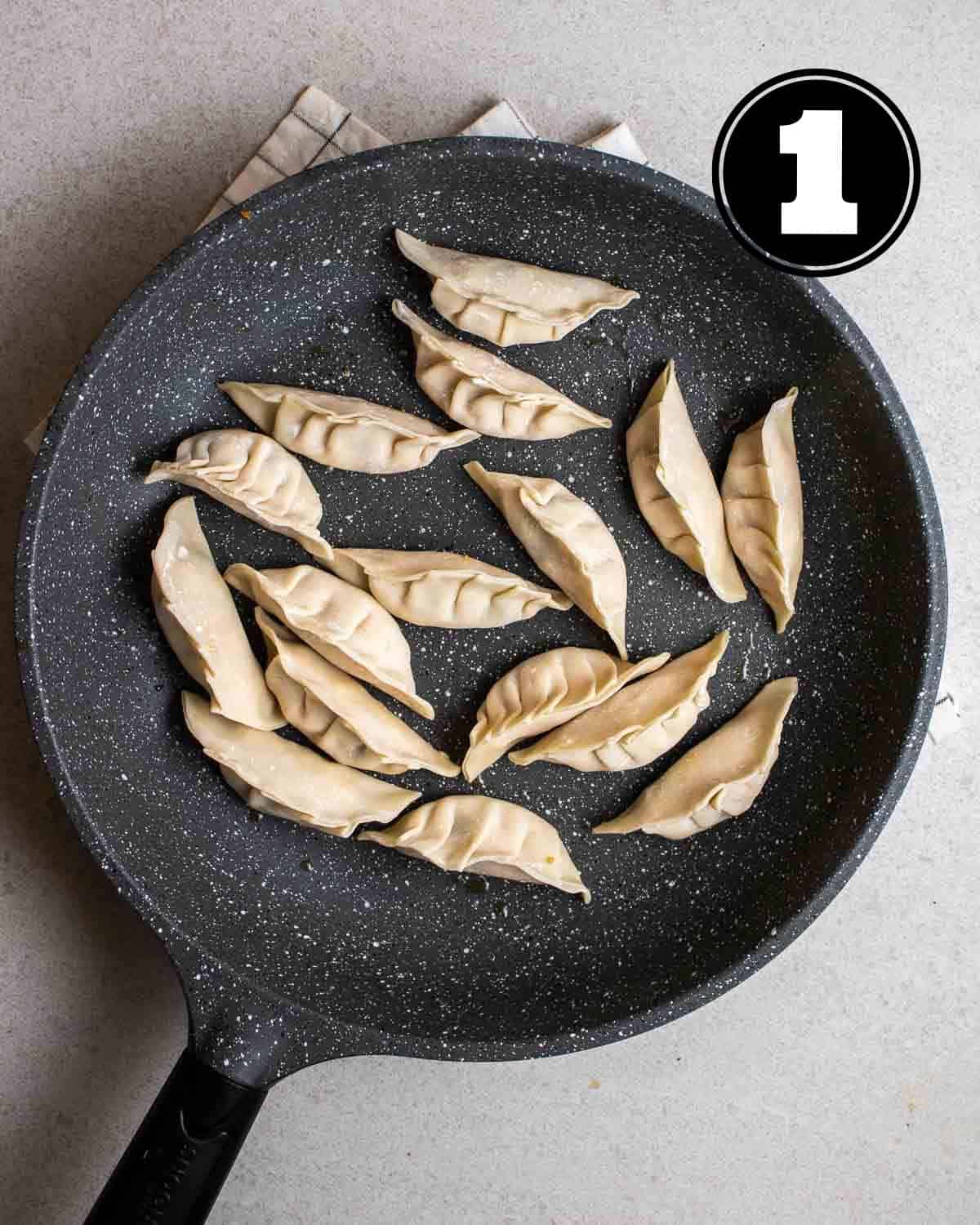 Uncooked dumplings in a pan on a folded white teacloth.