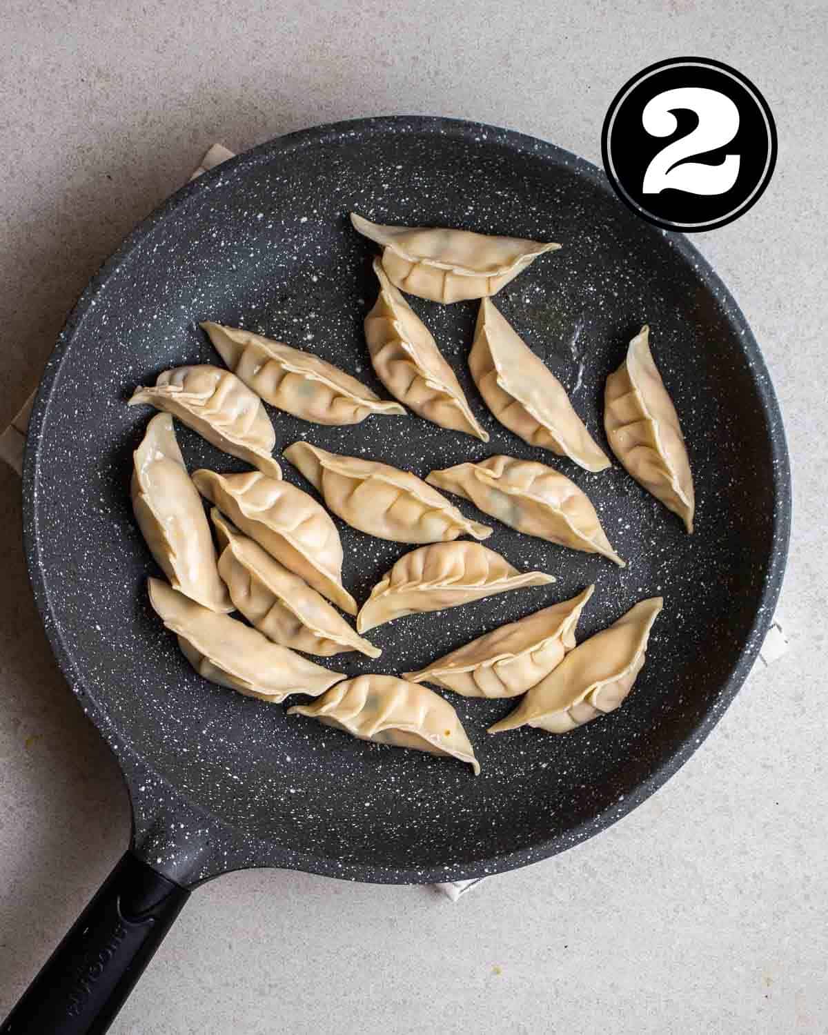Cooked dumplings in a pan on a white folded teacloth.