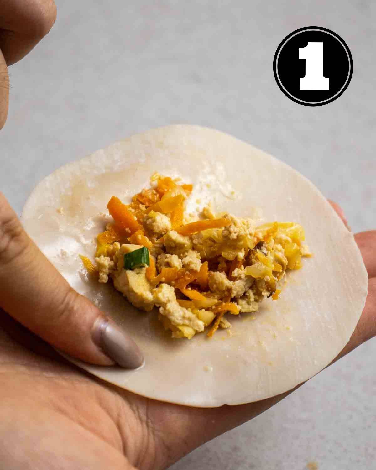 Holding a dumpling wrapper with filling.