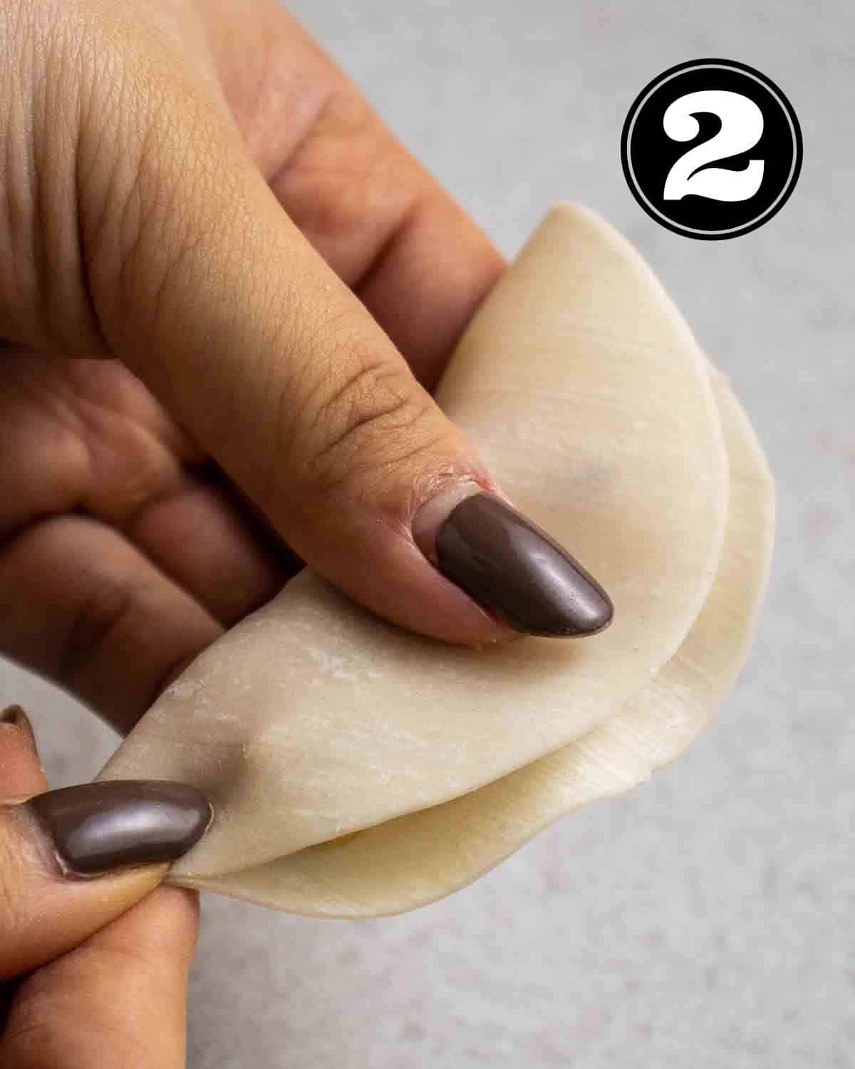 Folding dumpling wrapper in half.