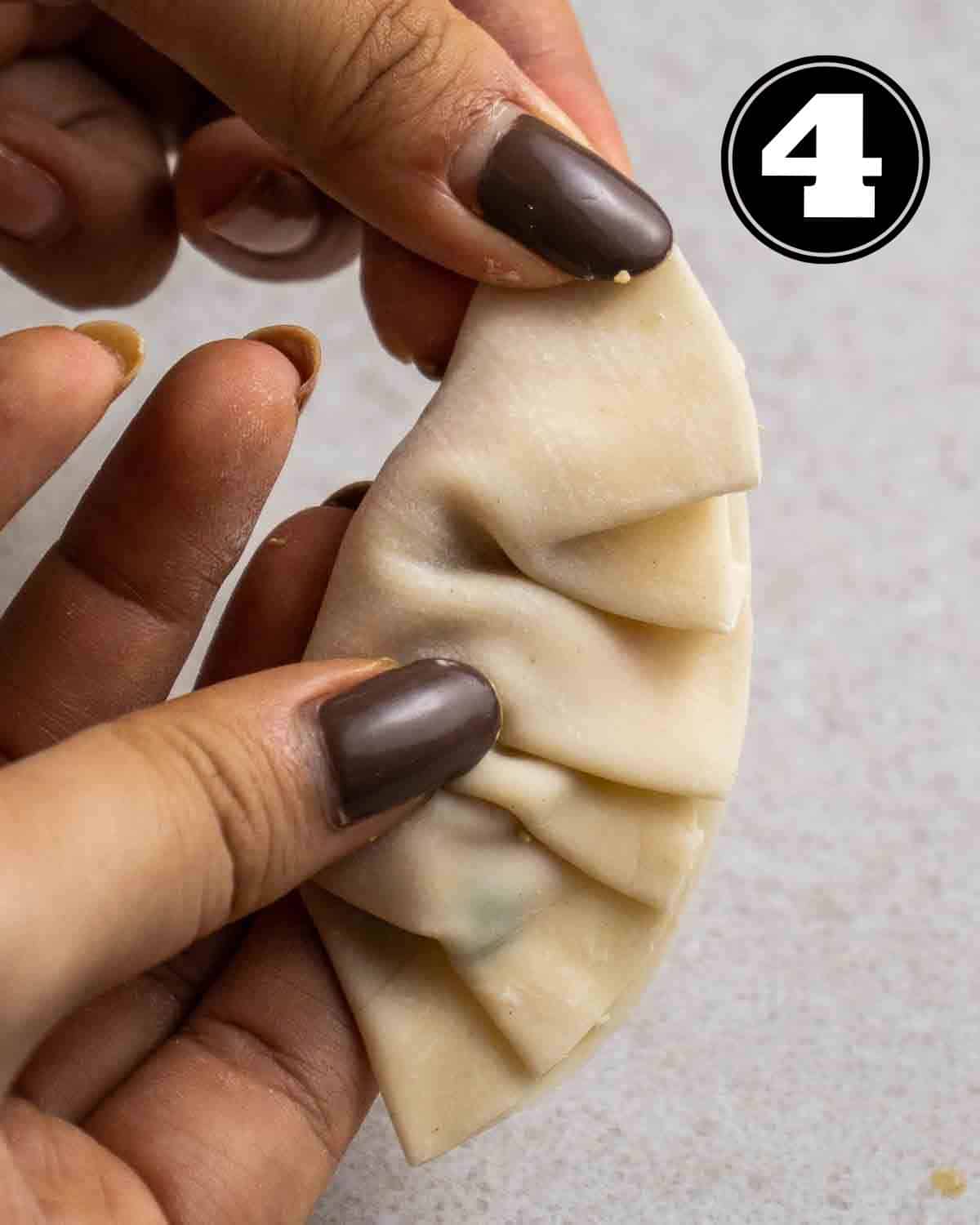 Holding a pleated dumpling.