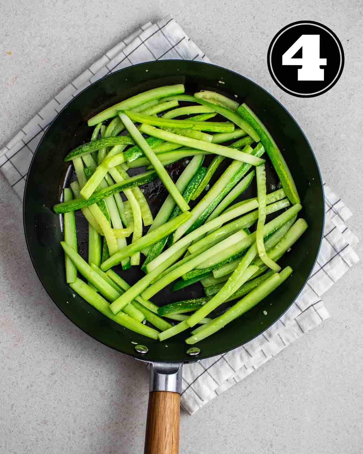 Cooked cucumber in a pan on a white folded teacloth.