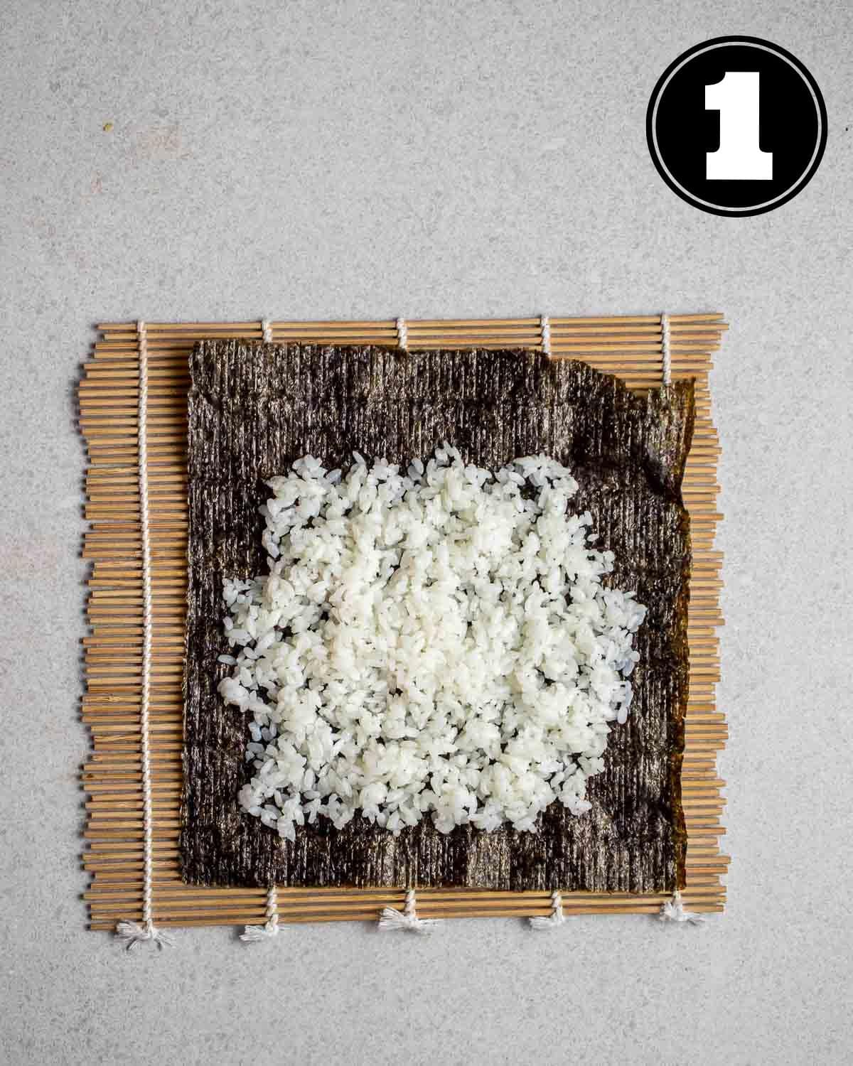Rice spread out on a nori sheet on a bamboo mat.