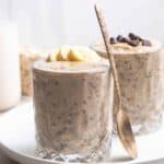 2 jar of overnight oats on a plate with a jar of oats and milk in the background.