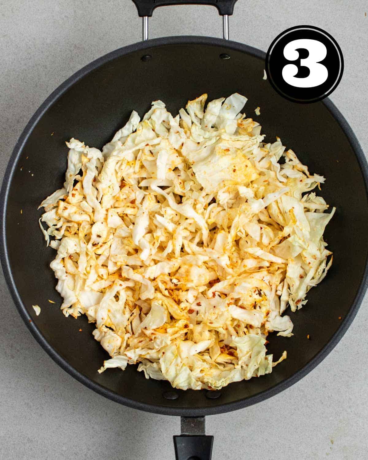 Raw cabbage added to a wok. 
