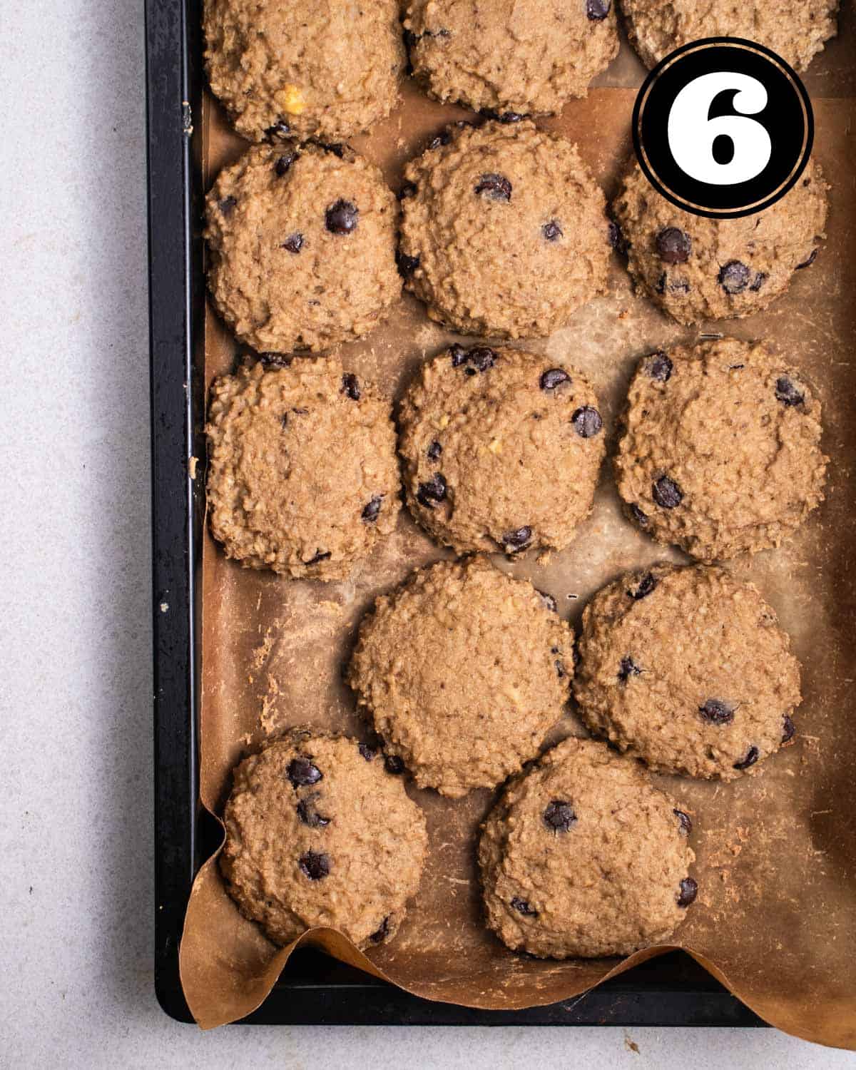 Baked cookies in a black baking tray lined with parchment paper.