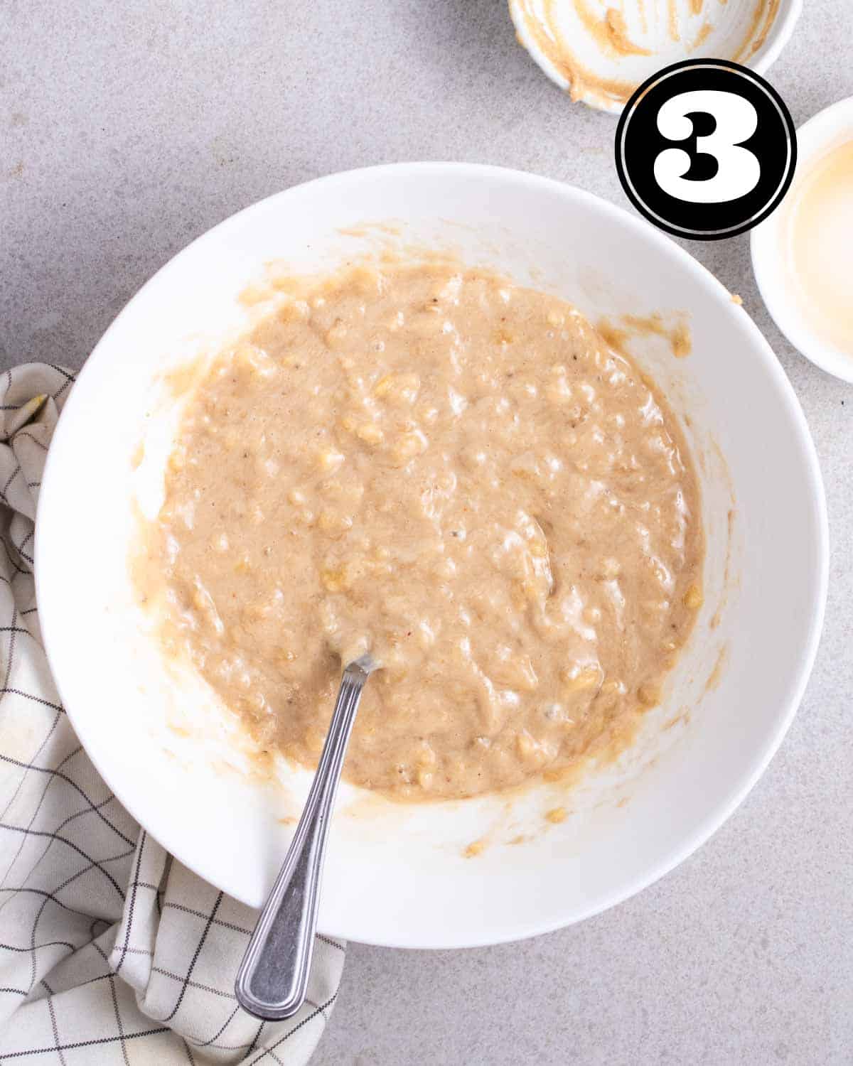 Wet ingredients in a white bowl with a fork beside.
