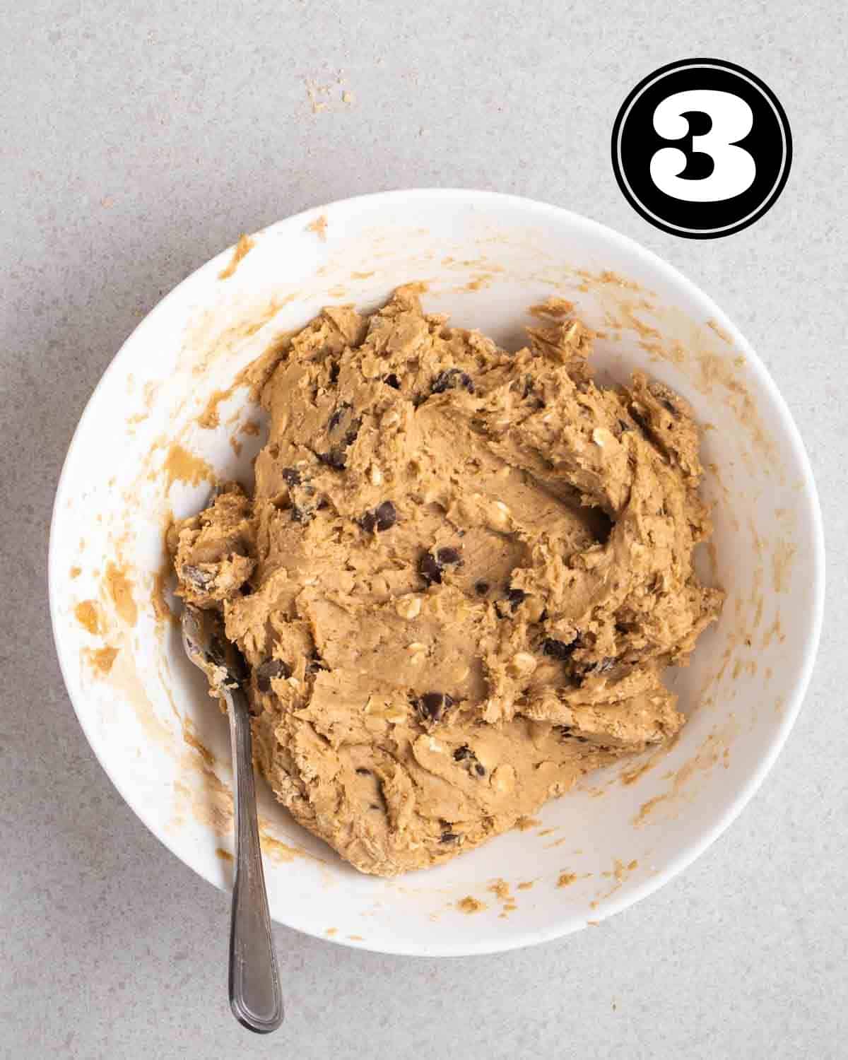 Cookie dough in a white bowl with a fork beside.
