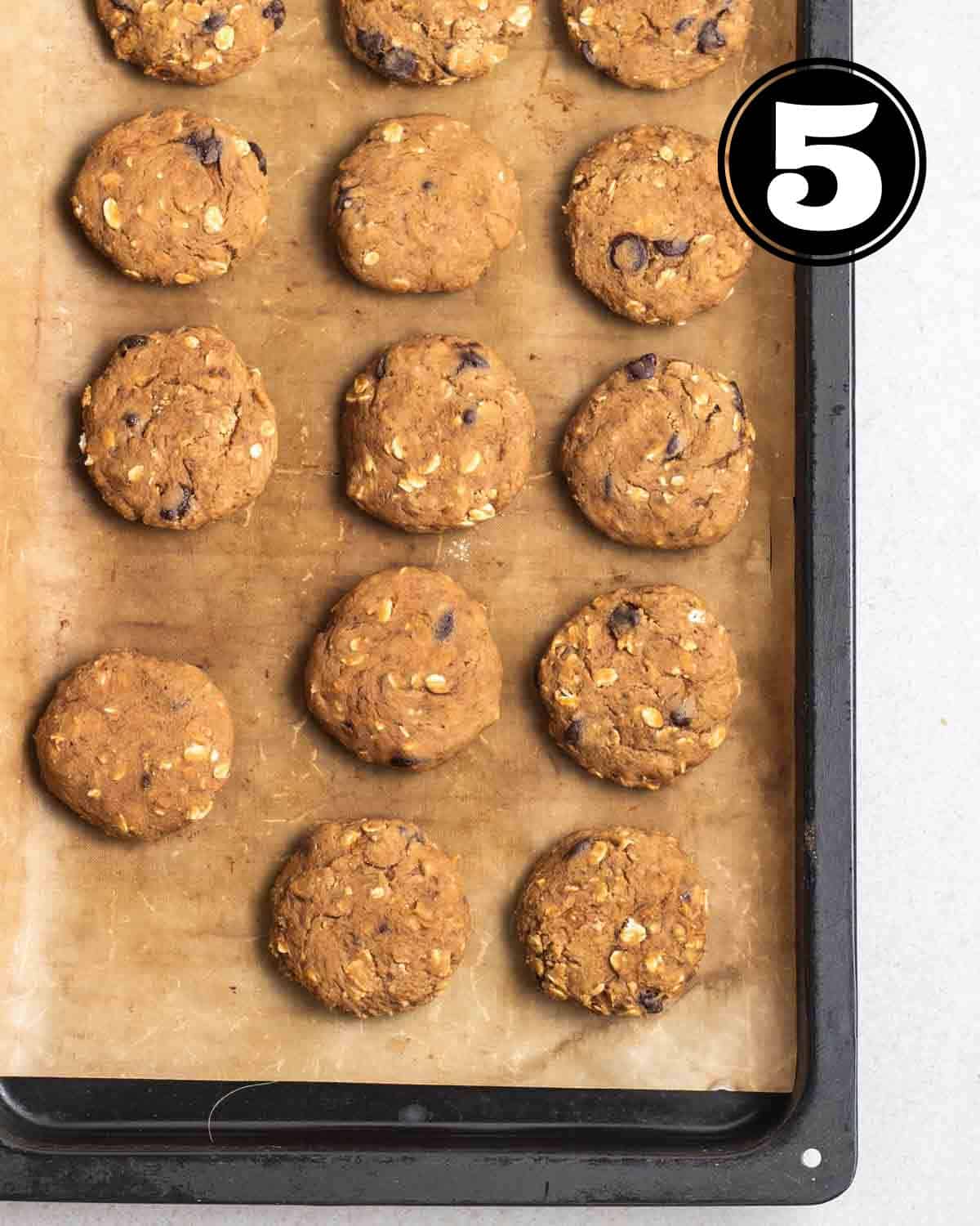 Baked cookies in a black baking tray lined with parchment paper.