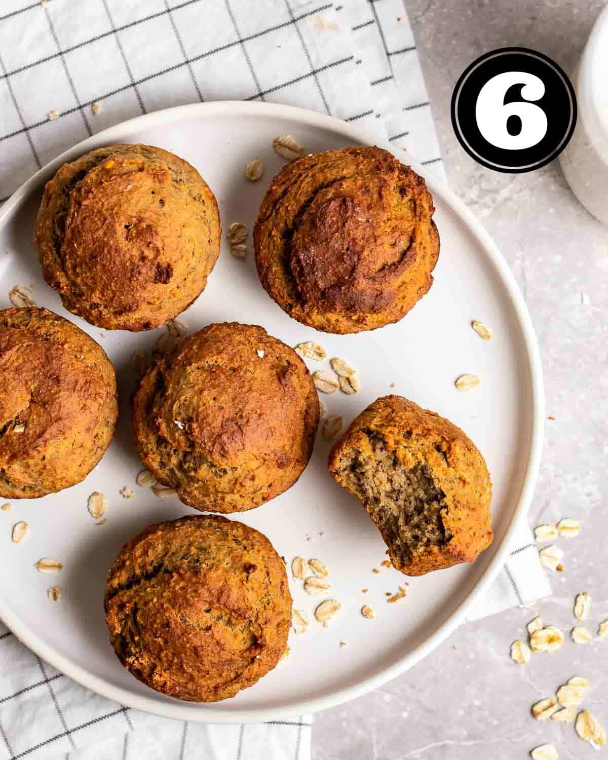 A plate of protein muffins on a white folded checkered teacloth with a jar of milk beside.